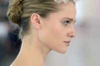 an elegant tight and sleek French twist updo with a large fabric flower on top is statement idea