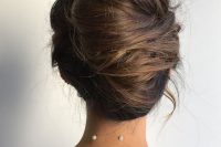 a messy French twist updo on long hair, with much texture and dimension and some locks down