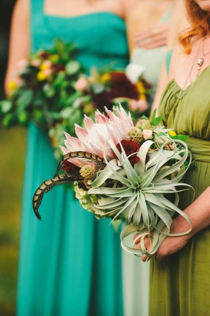 a bold wedding bouquet with air plants, a king protea and greenery and feathers is a unique solution with a lovely combo of everything unusual