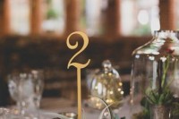 a cluster wedding centerpiece of an air plant, a gold table number, a cloche with succulents is a cool idea