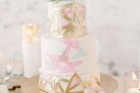 a glam wedding cake decorated with gold, pink and blue tringles painted and topped with an air plant is an ideal mid-century modern wedding dessert