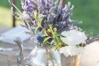a gorgeous wedding centerpiece of a silver teapot with lavender and thistles, a white blooms in a silver glass