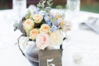 a chic rustic centerpiece of a dark weathered silver teapot with blush and blue blooms and a wooden table number