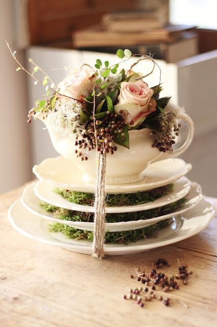saucepans with moss, a teapot with blush roses and greenery and baker's twine to secure