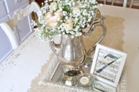 a vintage wedding centerpiece of a silver tray, a silver tea pot with blush roses and baby’s breath, candles and notes in a frame