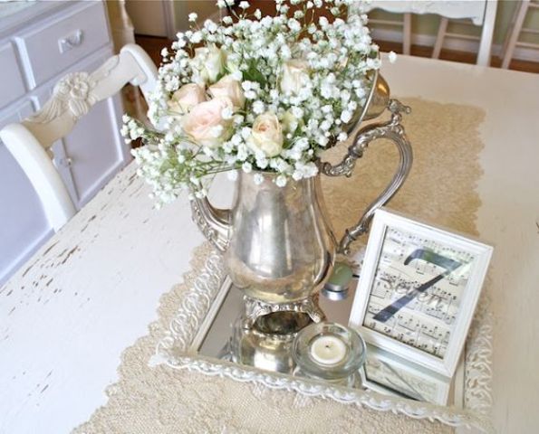 a vintage wedding centerpiece of a silver tray, a silver tea pot with blush roses and baby's breath, candles and notes in a frame