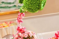 a whimsy wedding centerpiece made of green blooms shaped as tea pots and pink blooms as tea