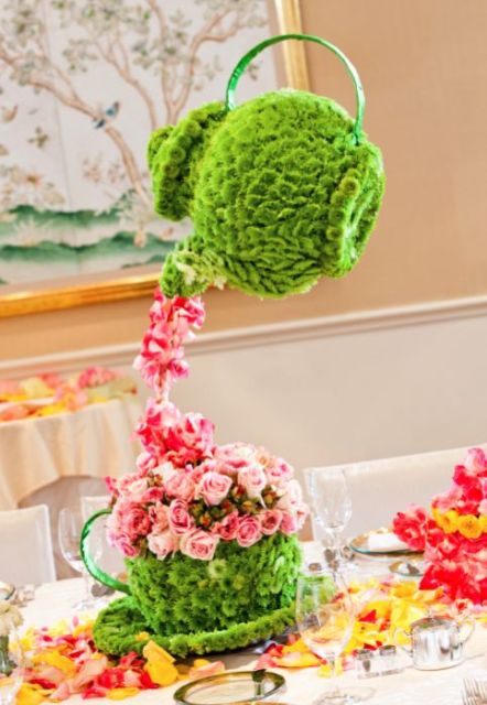 a whimsy wedding centerpiece made of green blooms shaped as tea pots and pink blooms as tea