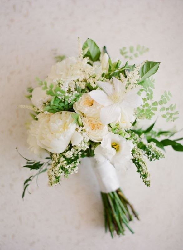 a textural white bridal bouquet with blooms and greenery of various kinds plus a neutral wrap