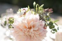a simple wedding centerpiece of a large blush dahlia and some greenery and wildflowers is a lovely idea for a neutral or pastel wedding