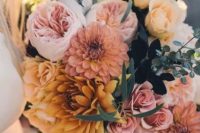 an earthy-tone wedding bouquet composed of yellow and pink dahlias, pink peony roses, yellow roses and greenery for a textural and dimensional touch