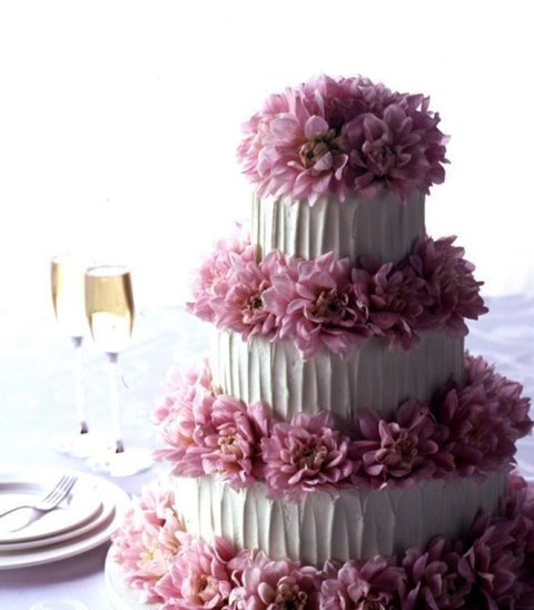 a white textural buttercream wedding cake decorated with pink dahlias all over the cake is a creative idea with a tender touch of color