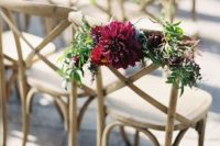 a bold wedding aisle chair decoration of greenery and a burgundy dahlia is a lovely idea for a bold fall wedding