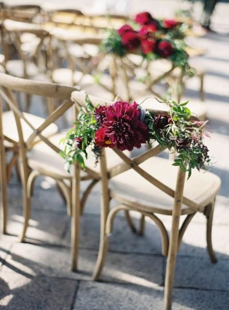 a bold wedding aisle chair decoration of greenery and a burgundy dahlia is a lovely idea for a bold fall wedding