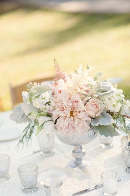a delicate neutral wedding centerpiece composed of blush dahlias, roses, white hydrangeas and pale greenery is perfect for spring and summer
