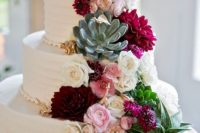 a white wedding cake decorated with white and pink blooms, succulents, greenery and burgundy dahlias is an amazing dessert for a contrasting wedding
