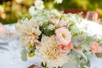 a pastel wedding centerpiece of blush dahlias, roses, neutral blooms and pale greenery is a delicate centerpiece for a spring or summer wedding in neutrals