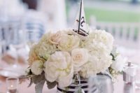 a simple and chic centerpiece of white blooms, a striped vase and a small boat on top
