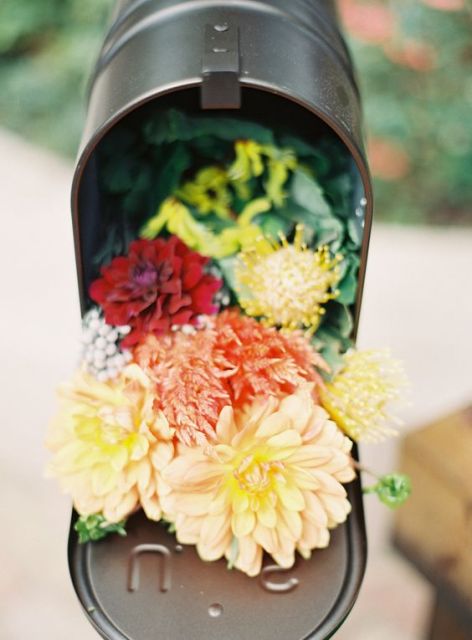 use a mailbox as a wedding decoration with bright blooms and greenery for an effortless and chic look