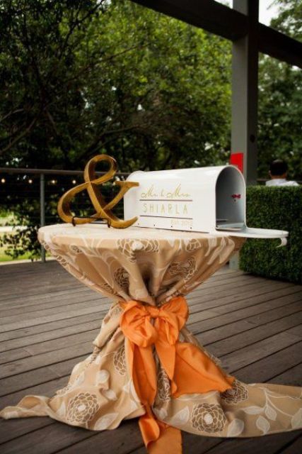 a mini table with a mailbox decorated with monograms and ampersand to leave wishes to the couple