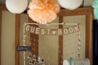 a guest book styled as a frame with clothespins and a mailbox next to it to leave wishes or to take pics from it