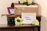 a chic copper mailbox with fresh hydrangeas and greenery on it plus a frame with your names for leaving wishes