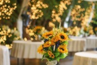 a rustic wedding centerpiece of a wooden slice, sunflowers and greenery and a candle lantern