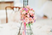 a Parisian-themed Eiffel Tower centerpiece with pink blooms and ribbons is a cool quirky idea for your party