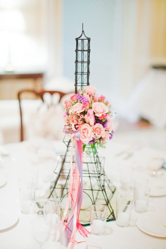 a Parisian themed Eiffel Tower centerpiece with pink blooms and ribbons is a cool quirky idea for your party