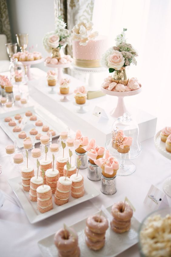 a beautiful blush Parisian-style sweets table with lots of delicious desserts, pink meringues and a pink cake, with blush blooms