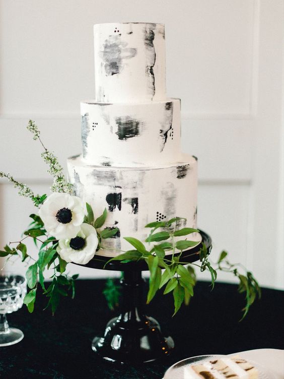 a black and white wedding cake with brushstrokes, greenery and white anemones is a beautiful graphic solution