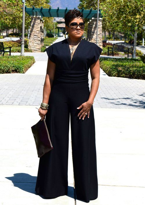 a black jumpsuit with wideleg pants, cape sleeves, a high waist and a statement necklace for a statement