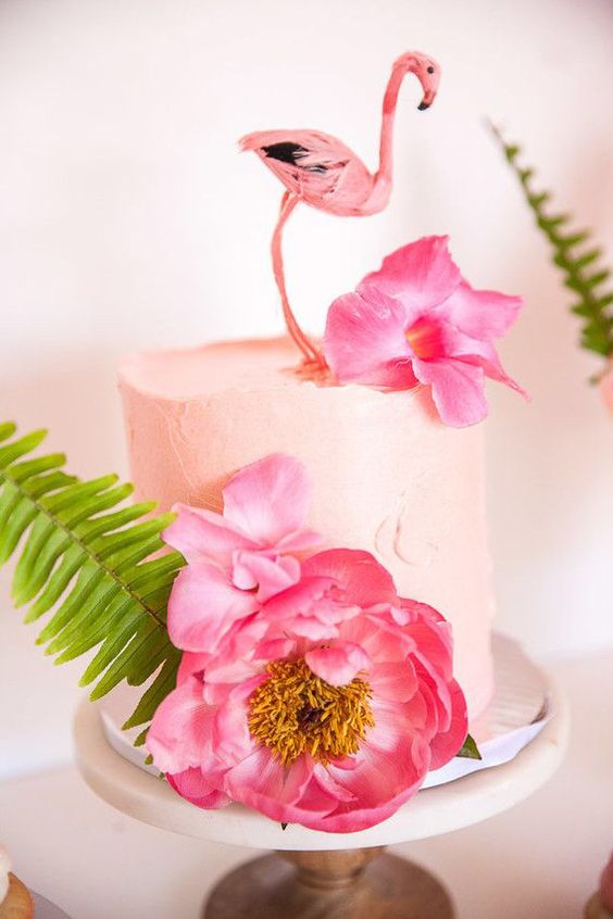 a blush bridal shower cake with large pink blooms, a leaf and a flamingo topper for fun