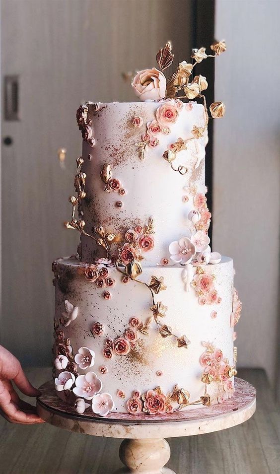 a blush wedding cake decorated blush cherry blossom and branches and leaves plus gilded touches looks veyr beautiful and chic