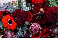 a bold and catchy wedding centerpiece of red anemones, red roses and burgundy dahlias, greenery and berries for a bold wedding