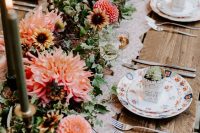 a bold monochromatic wedding tablescape with pink and orange dahlias, greenery and dark green candles, floral print plates and neutrla cutlery