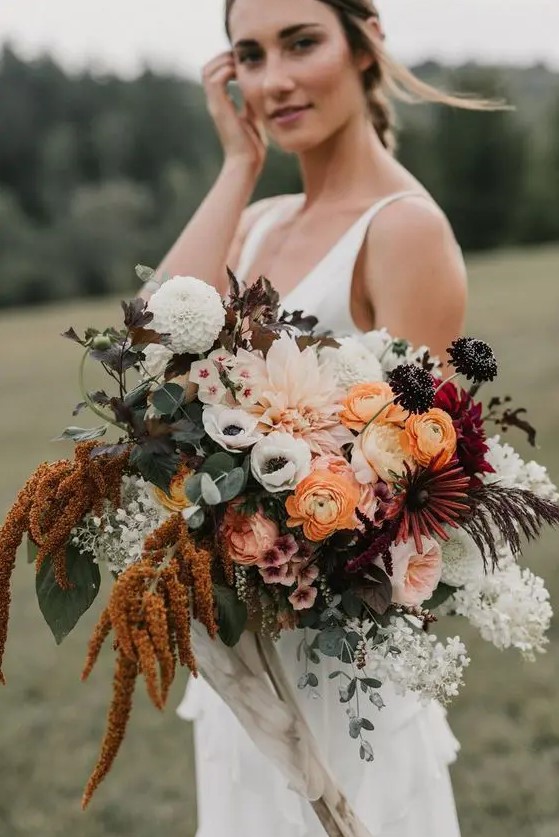 a bold summer wedding bouquet with burgundy, rust, pink, orange and white blooms of various kinds including anemones