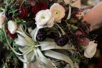 a bold wedding bouquet of burgundy, deep purple and blush blooms, greenery and air plants is a lovely and bright solution