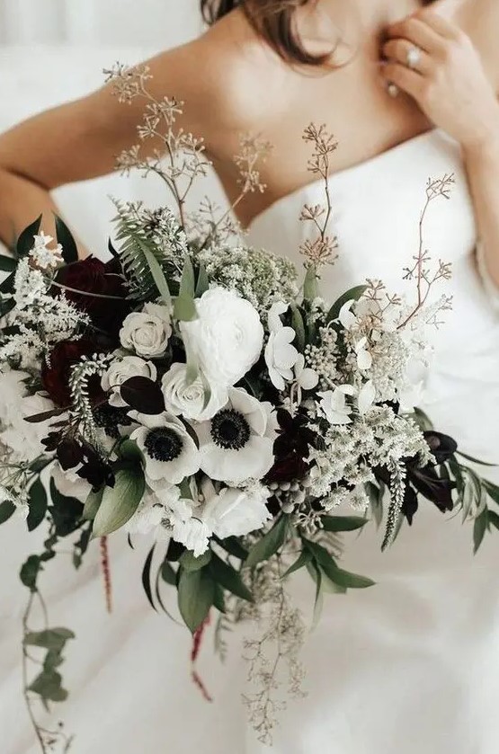 a bold wedding bouquet of white anemones and ranunculus, greenery and blooming branches is a stylish idea for a bride who loves contrasts