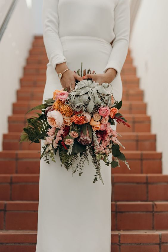 a bold wedding bouquet with pink, blush and orange blooms and greenery and air plants is an amazing idea