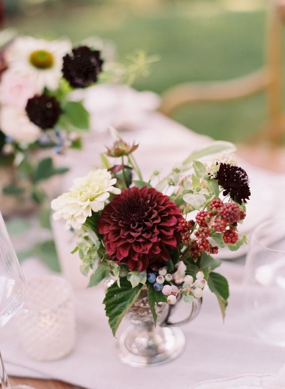 a bold wedding centerpiece of white and depe purple dahlias, berries and greenery for a fall wedding
