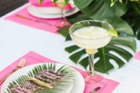 a bright and glam torpical bridal shower tablescape with hot pink placemats, a tropical leaf and a pink menu on acryl plus a bright floral arrangement