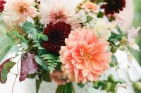 a bright fall wedding bouquet of burgundy, blush and orange dahlias, greeneyr and fern is a gorgeous idea