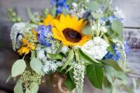 a bright summer wedding bouquet of blue and white blooms, sunflowers and textural greenery