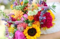 a bright summer wedding bouquet with hot pink peonies, sunflowers, some wildflowers, orange dahlias and seed pods is a lovely idea