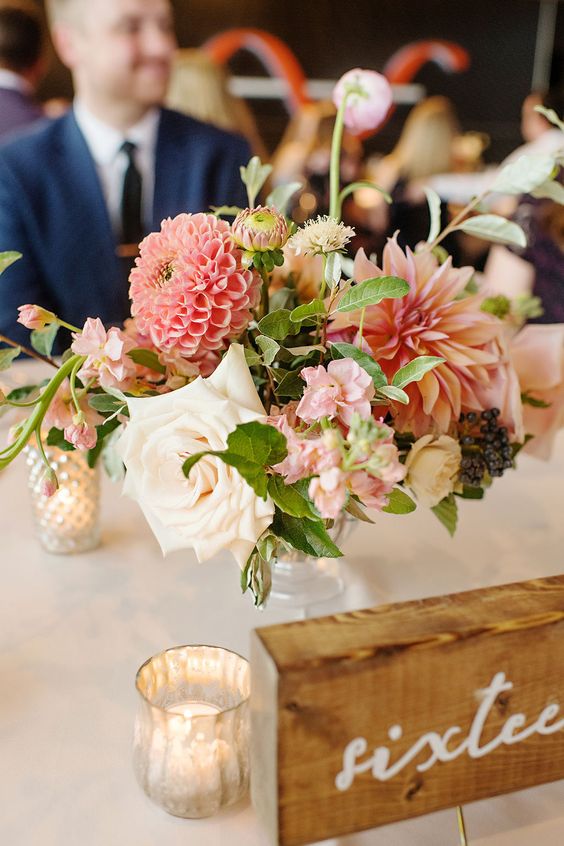 a bright summer wedding centerpiece with pink dahlias of different kinds, white roses and some simple greenery