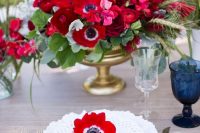 a bright wedding centerpiece of red anemones and ranunculus, greenery and grasses for a bold wedding