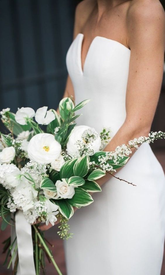 a catchy white wedding bouquet of peonies and roses, some blooms on branches and greenery and leaves