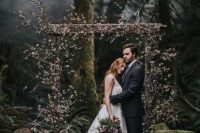 a cherry blossom wedding arch placed in the woods is a creative idea for a moody spring wedding, it will contrast the forest around a lot