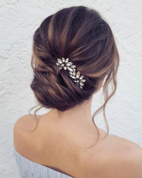a chic French twist updo with a volume on top and locks down with a rhinestone hairpiece